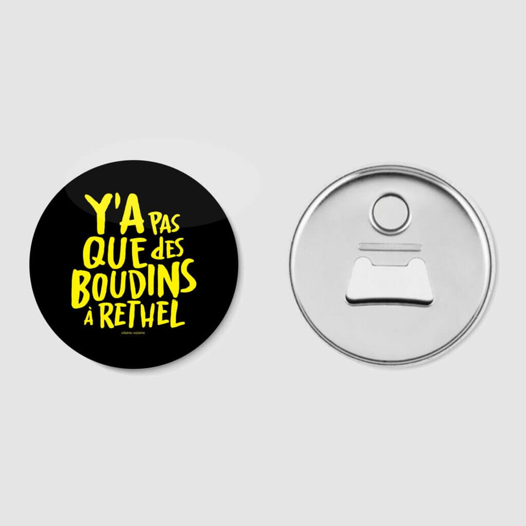 Décapsuleur magnétique noir mat, avec le texte y'a pas que des boudins à Rethel en jaune, de vilains-voisins imprimerie et studio de design graphique à Rethel, dans les Ardennes.