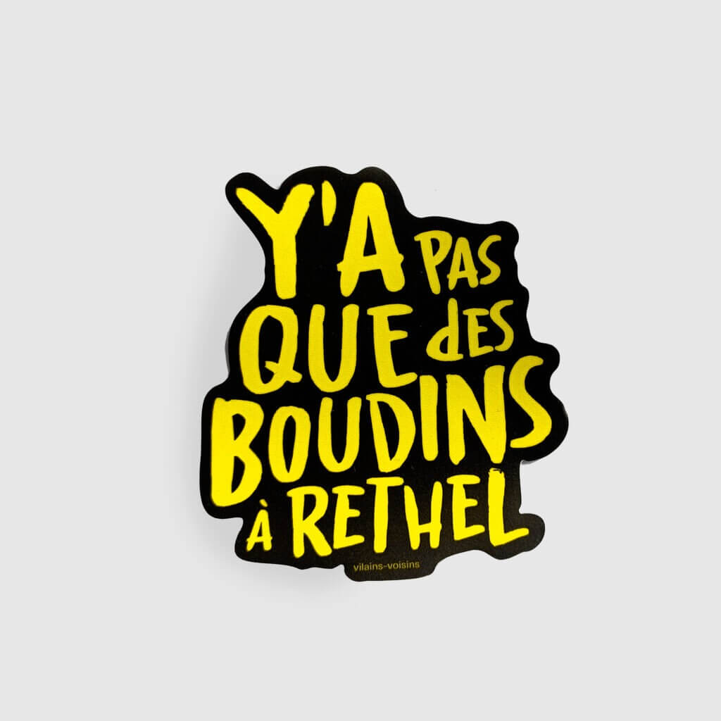 Adhésif noir, avec le texte y'a pas que des boudins à Rethel en jaune, de vilains-voisins imprimerie et studio de design graphique à Rethel, dans les Ardennes.